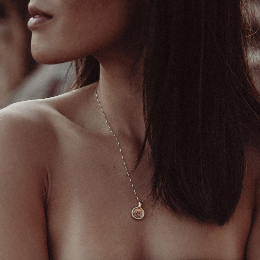 Woman wearing a delicate gold necklace with a small pendant.