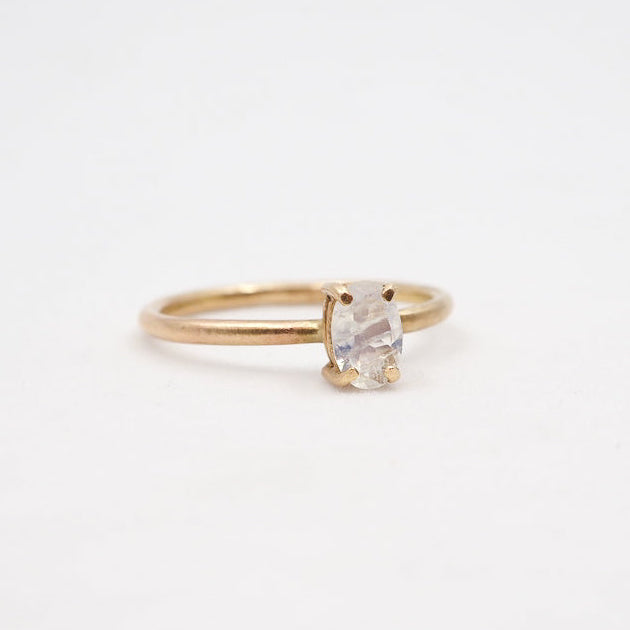 Gold ring with a clear gemstone on a light beige background