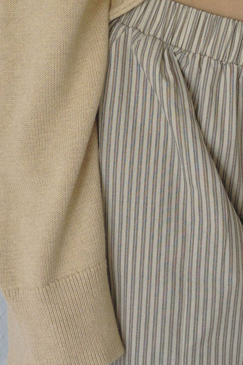 Close-up of a beige sweater and striped pants