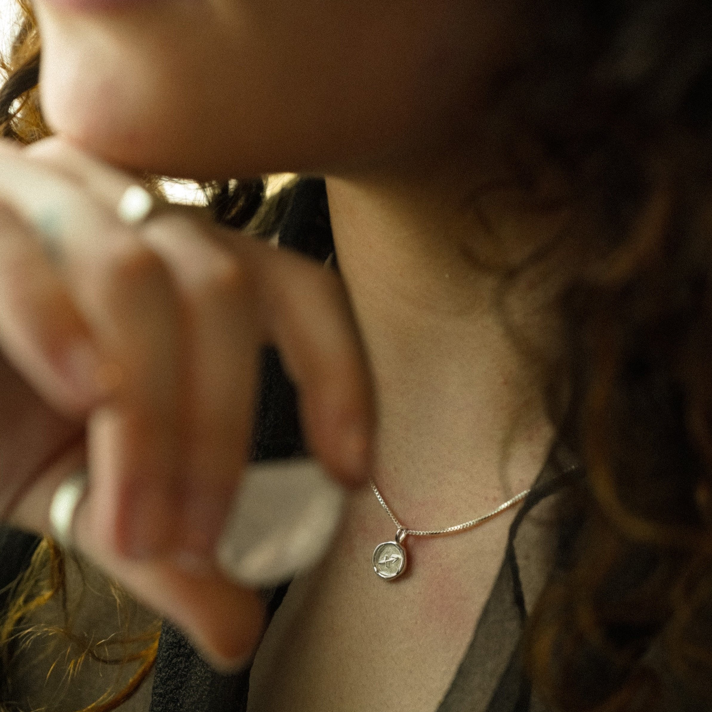 A person wearing a 10k gold necklace with a pendant, part of the Twelve Houses Collection.