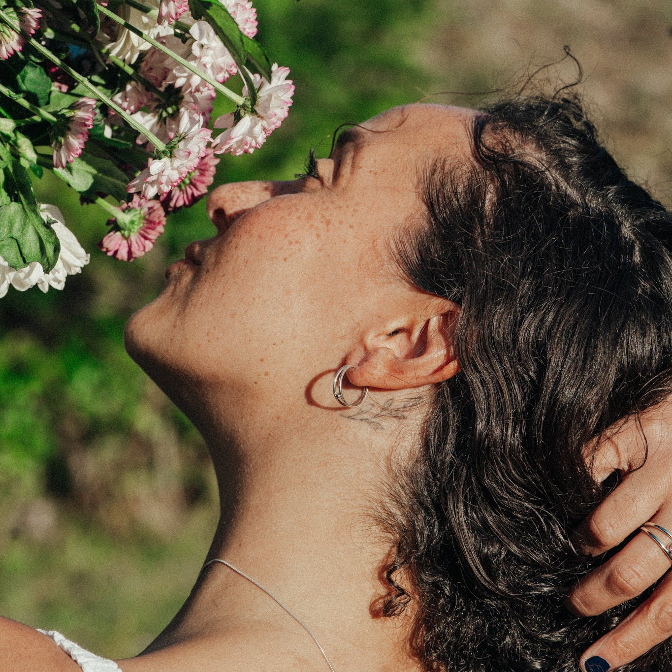 Person smelling flowers with a blurred natural background