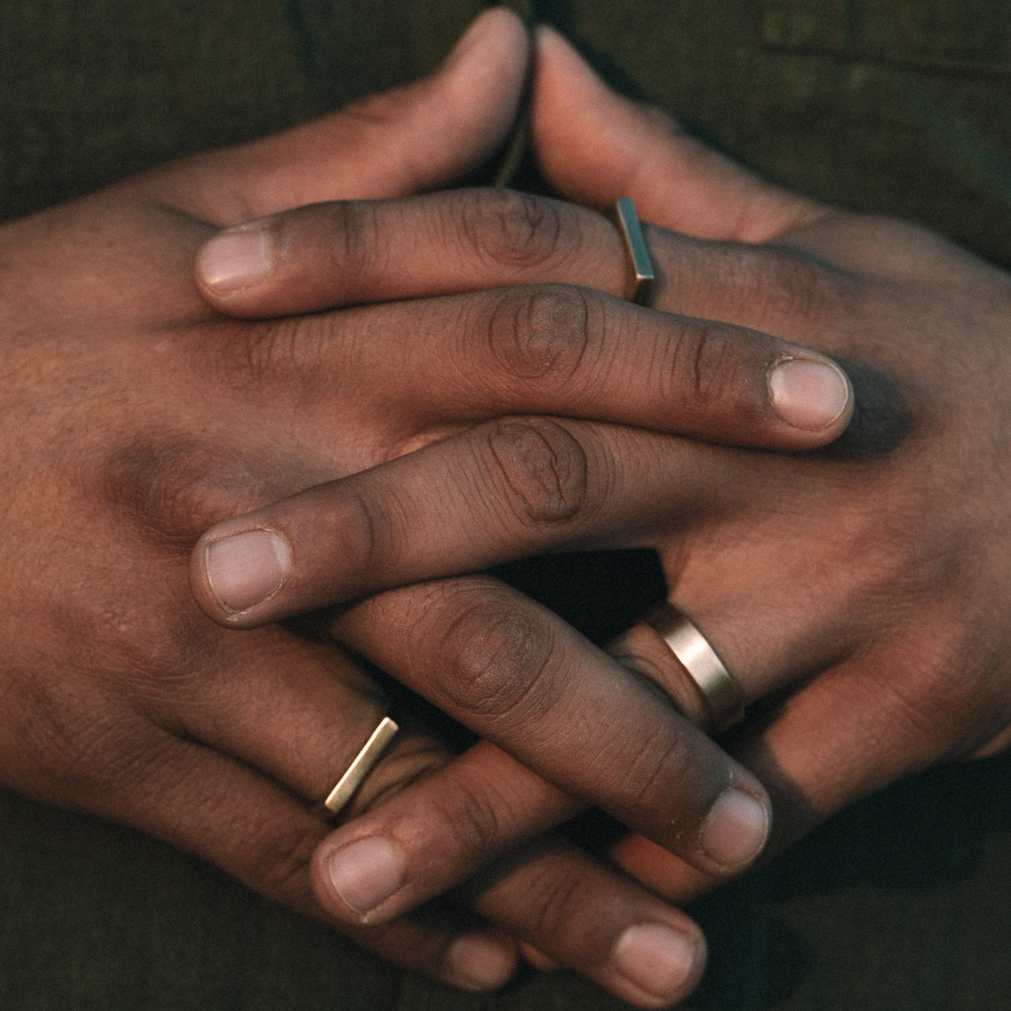 Close-up of hands with gold rings on a dark background