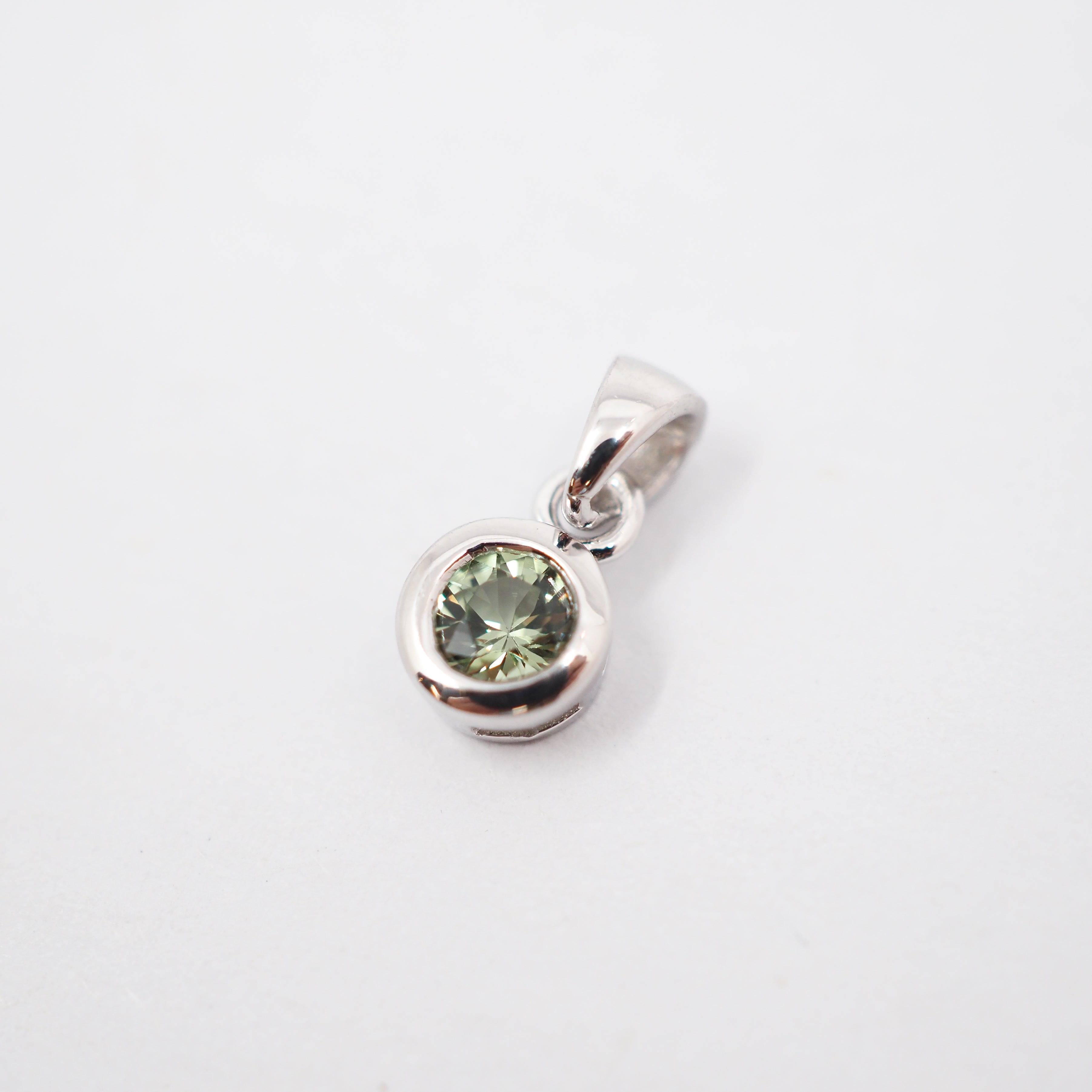 A sterling silver pendant featuring a bezel-set round green gemstone, shown on a clean white background.