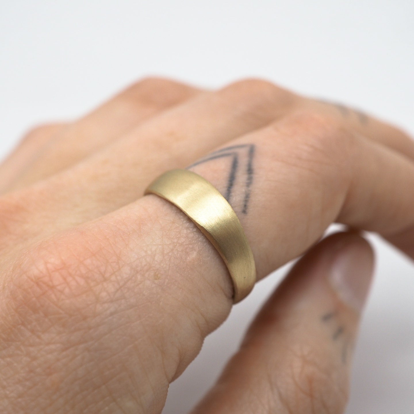 Gold ring on a person's finger with a white background