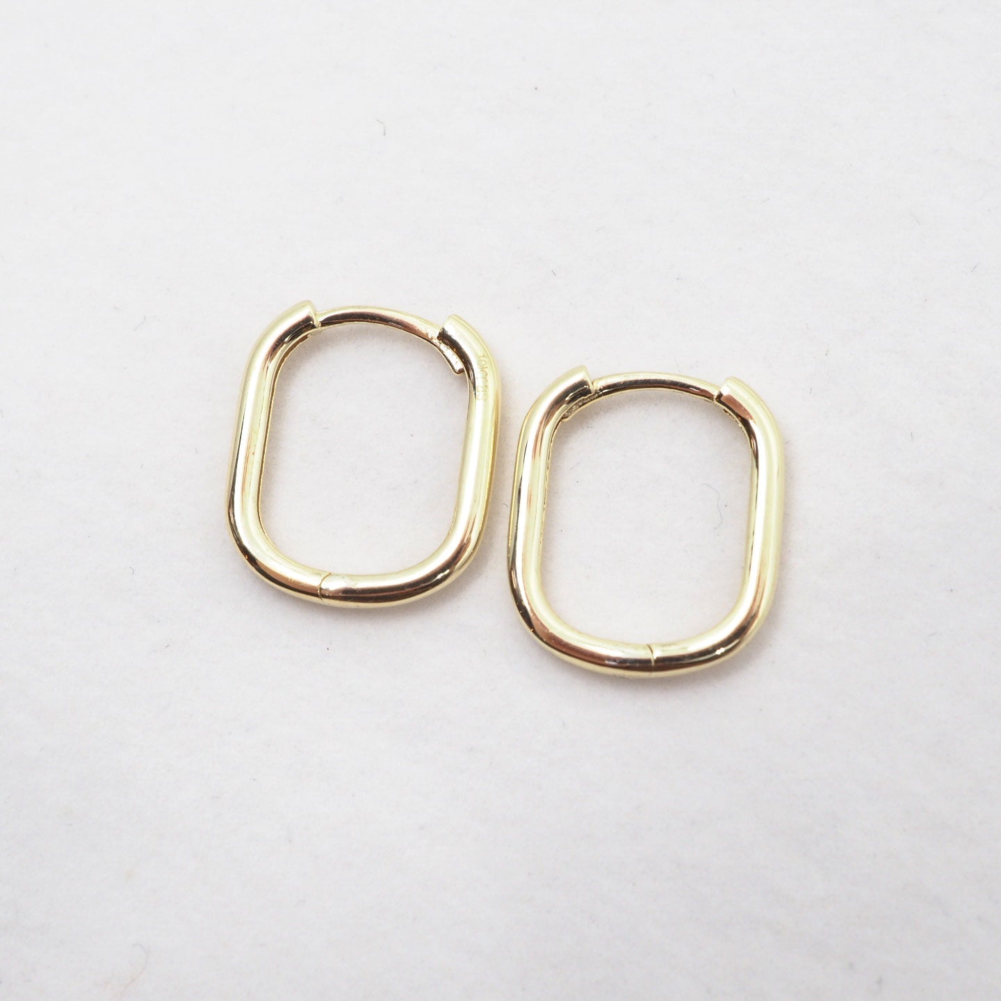 Gold hoop earrings on a light gray background