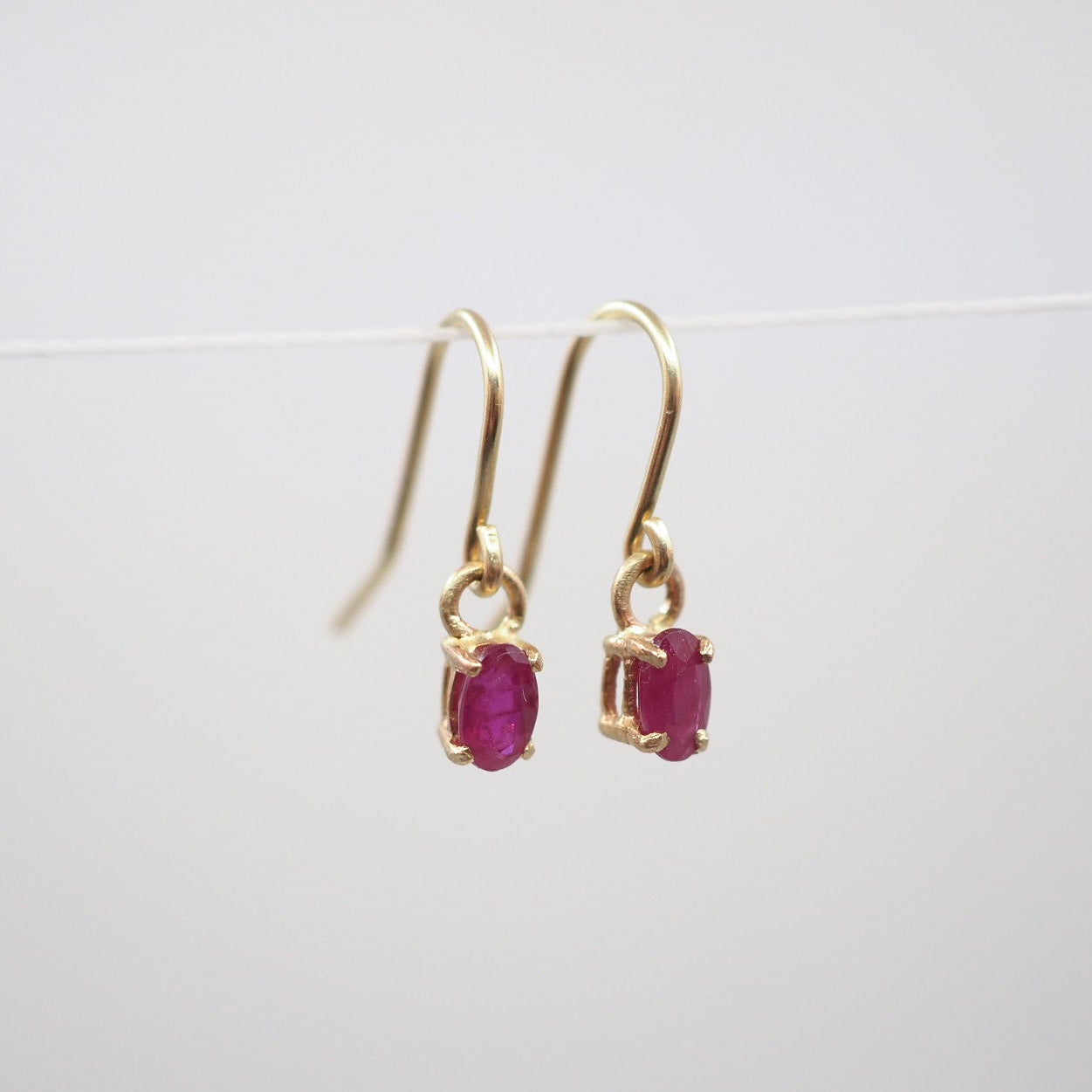 Gold earrings with red gemstones on a white background
