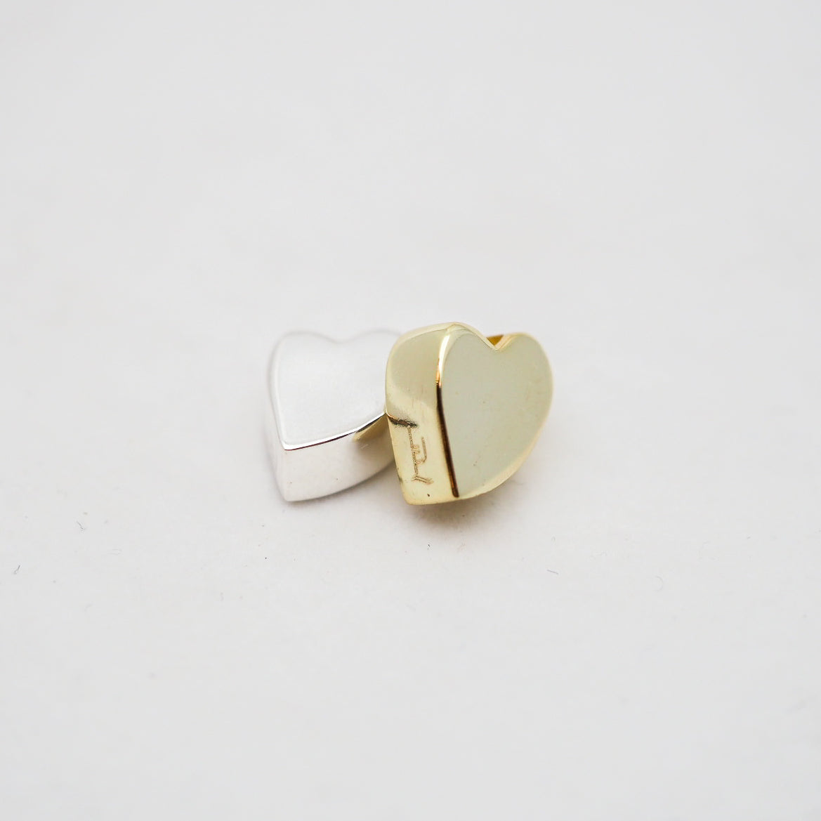 Gold and silver heart-shaped pendants on a light gray background