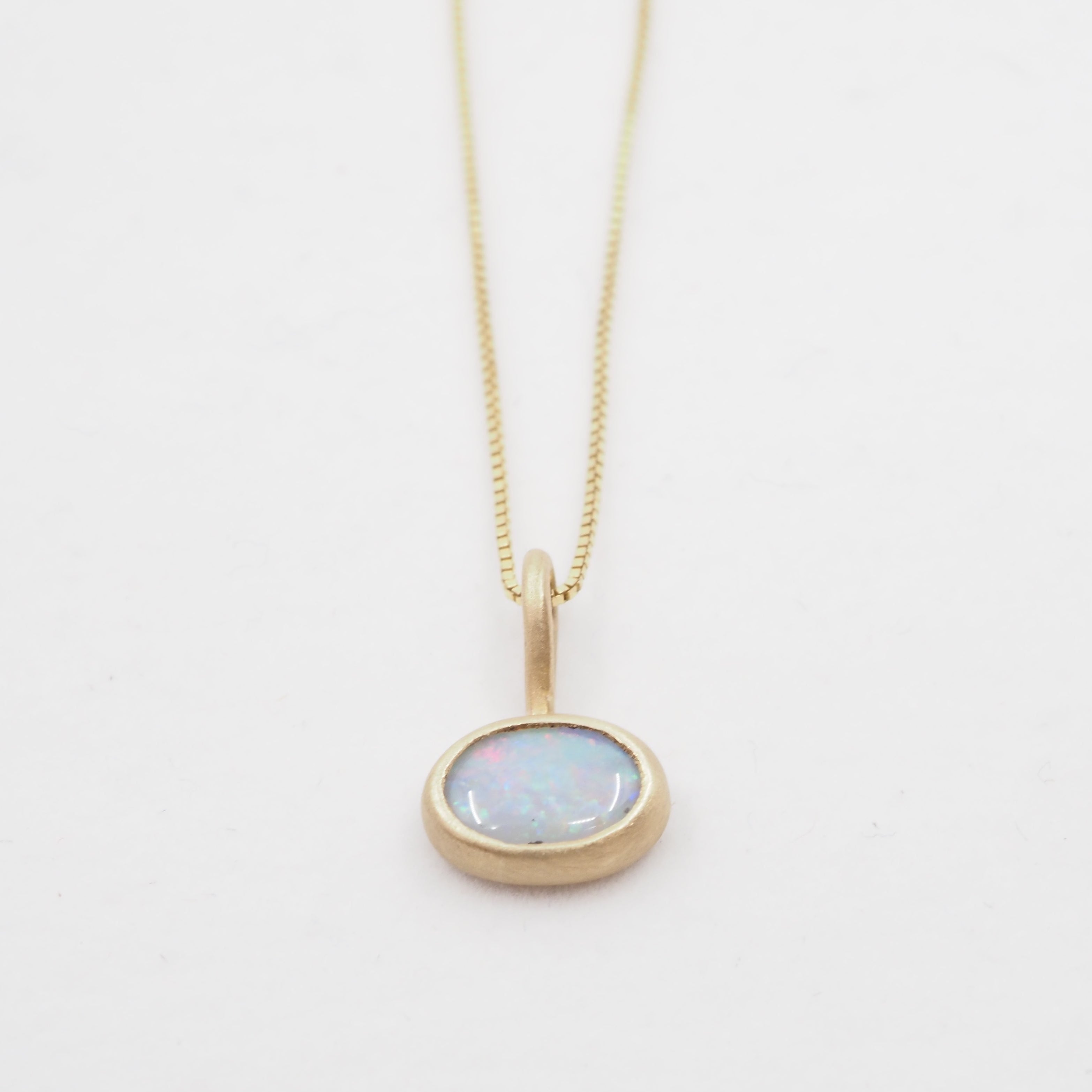 Gold necklace with an opal pendant on a white background
