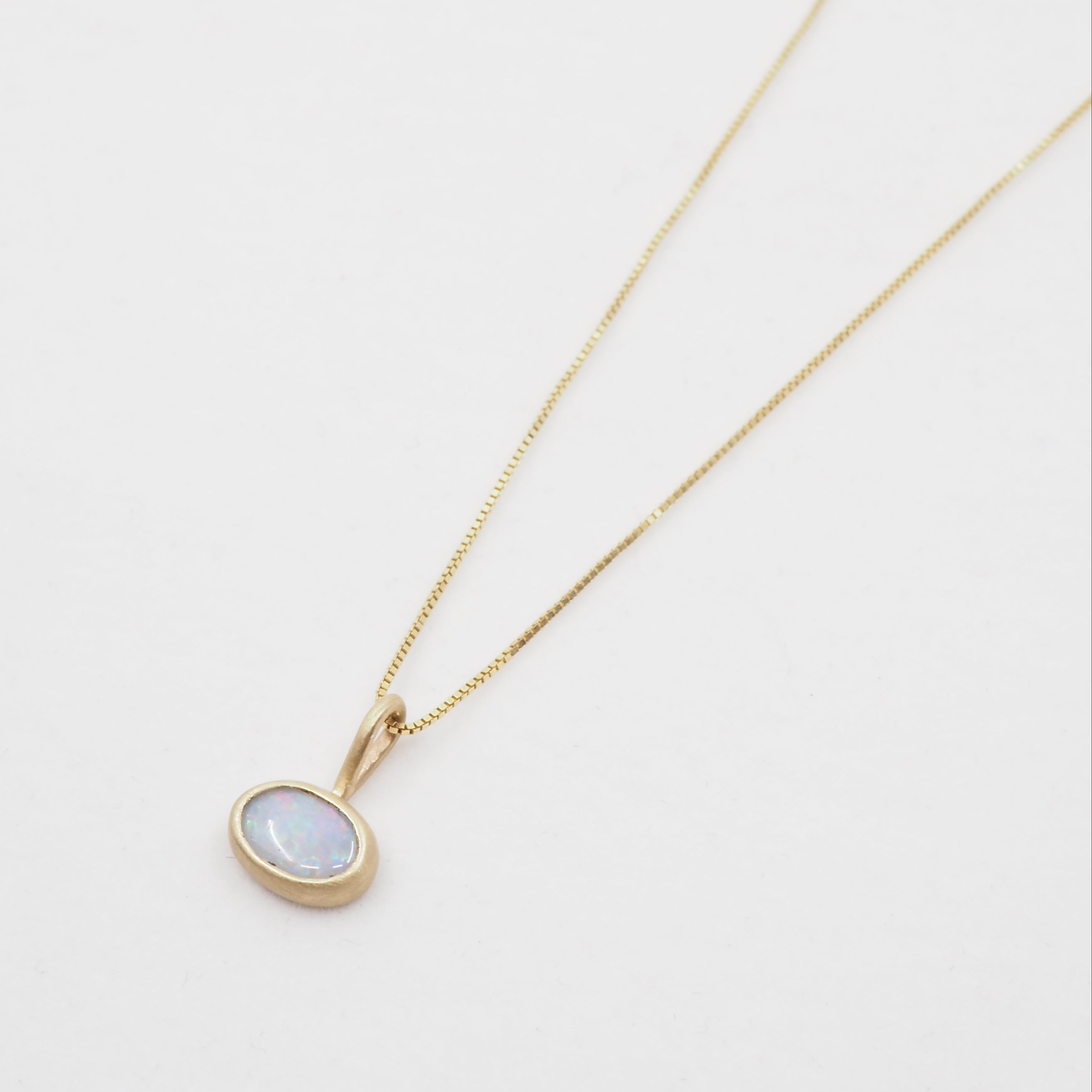 Gold necklace with a round pendant on a light gray background