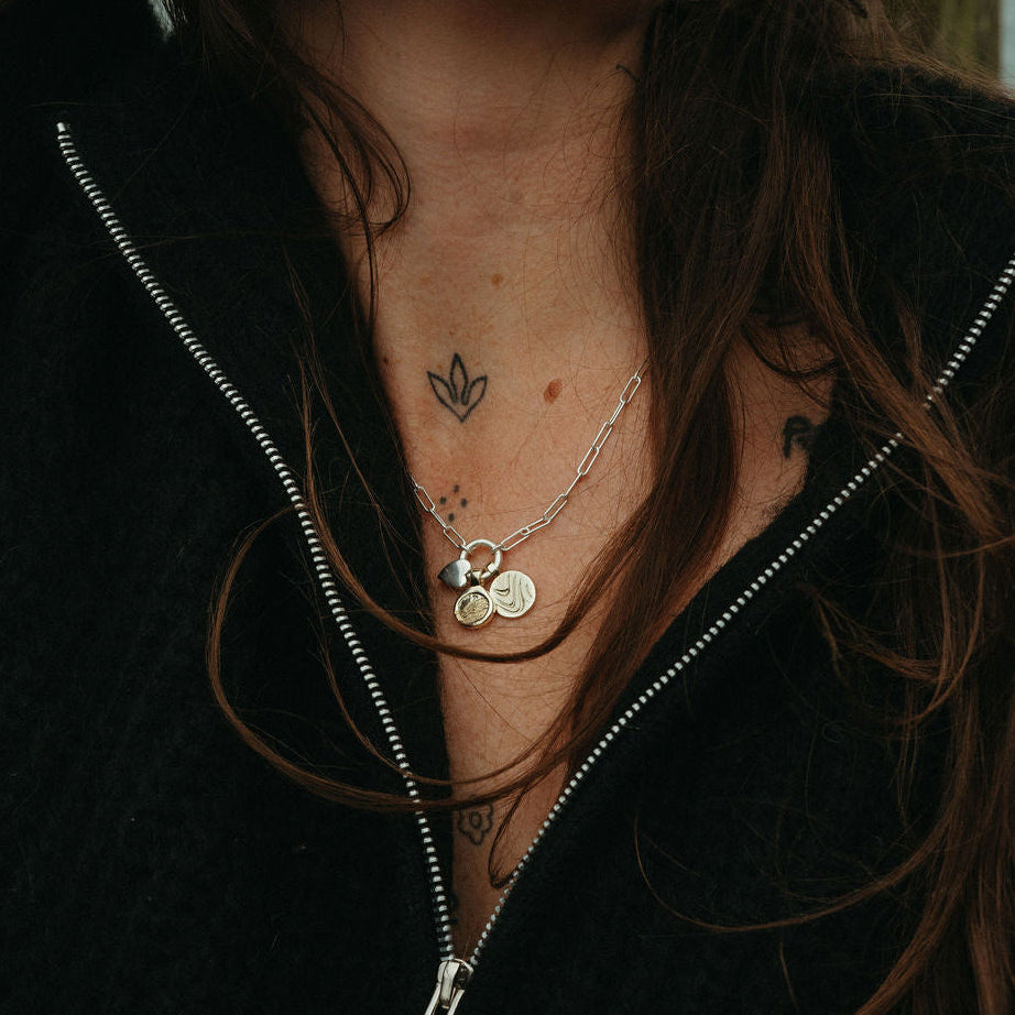 Person with long hair and necklaces against a blurred background
