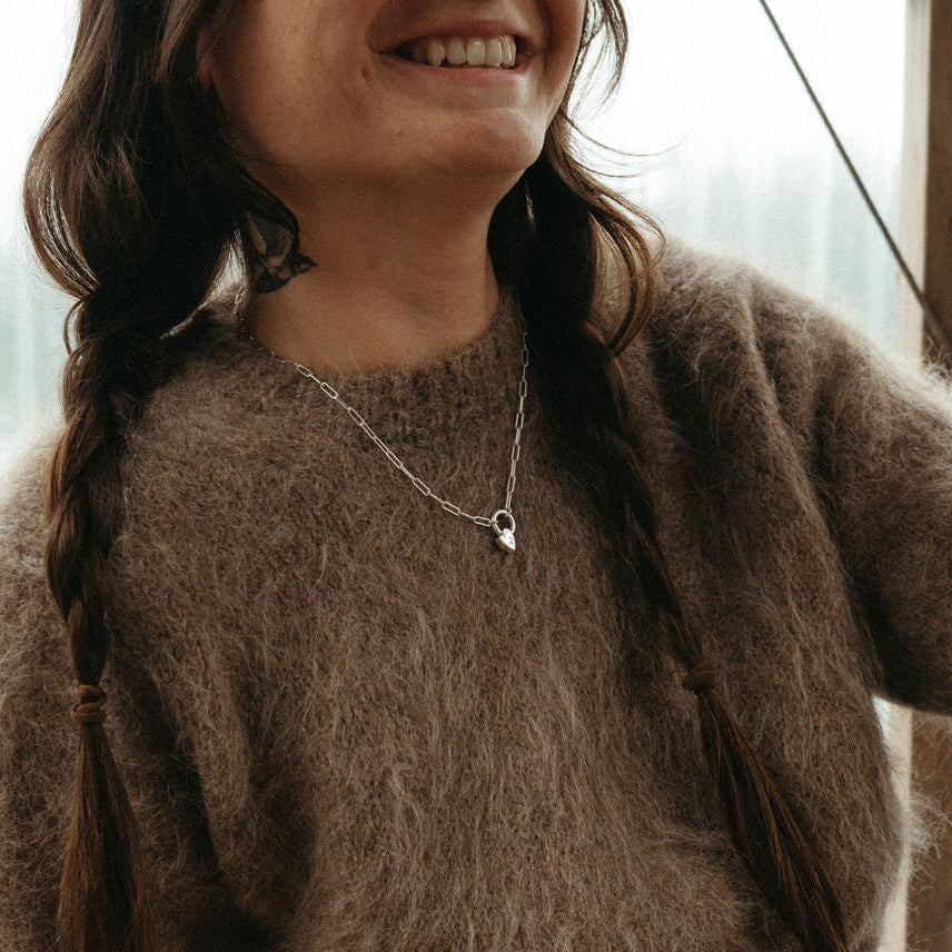 Person wearing a brown sweater sitting indoors with a blurred background