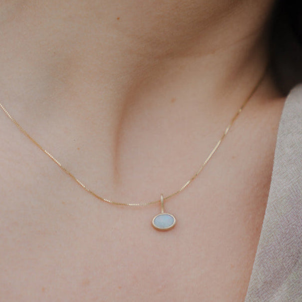 Gold necklace with a small pendant on a person's neck