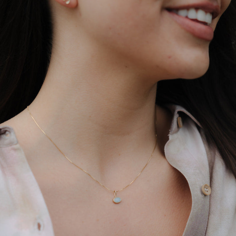 Close-up of a woman wearing a gold necklace with a small pendant.