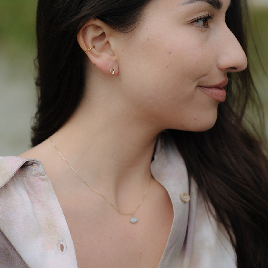 Close-up of a woman wearing gold earrings and a necklace with a blurred background