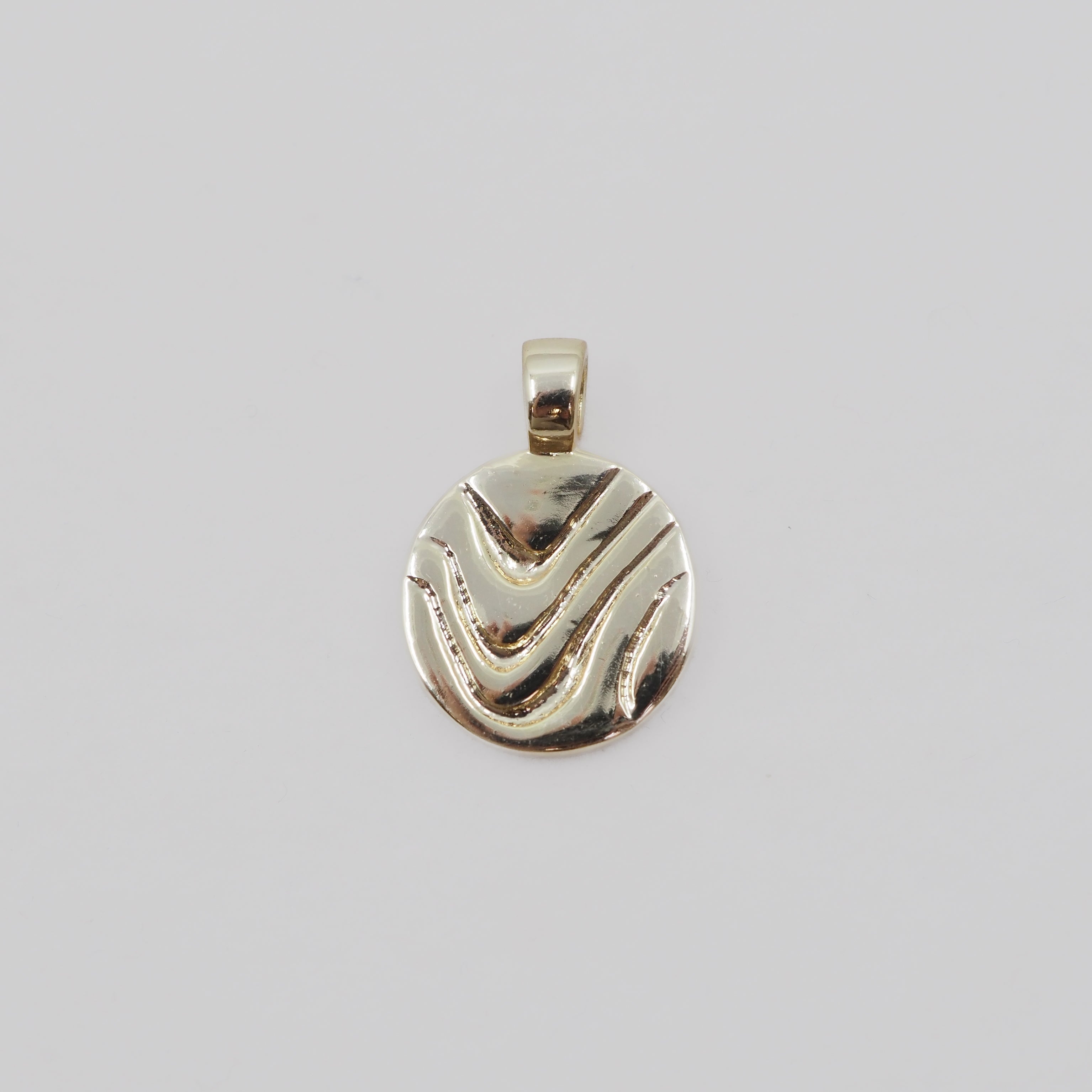 Gold pendant with wavy design on a light gray background