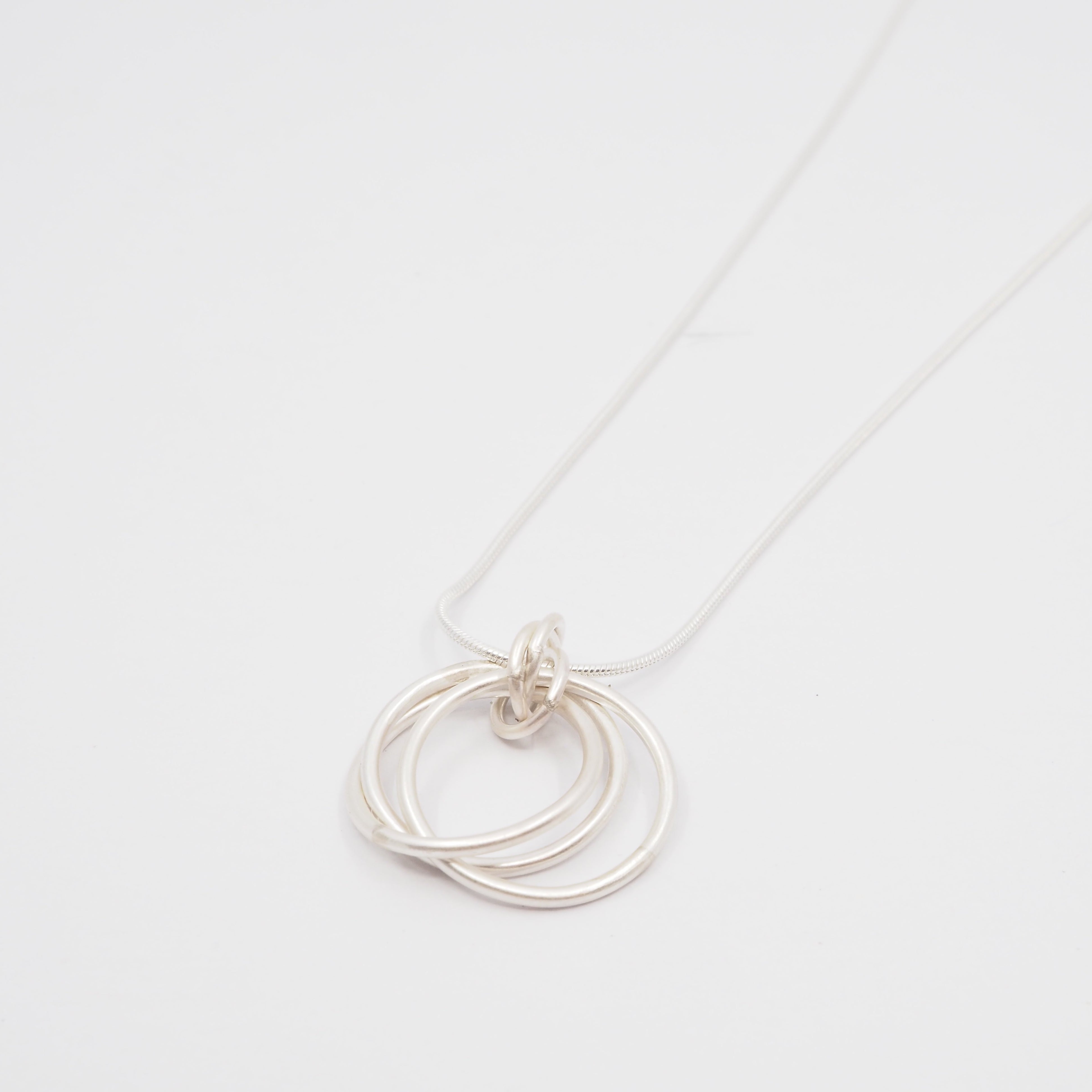 Silver necklace with interlocking rings on a white background