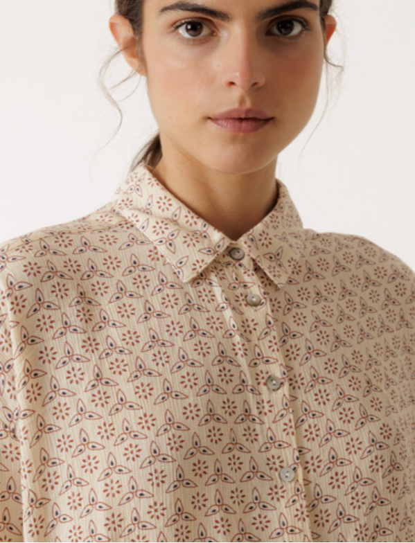 Woman wearing a patterned blouse with a neutral background