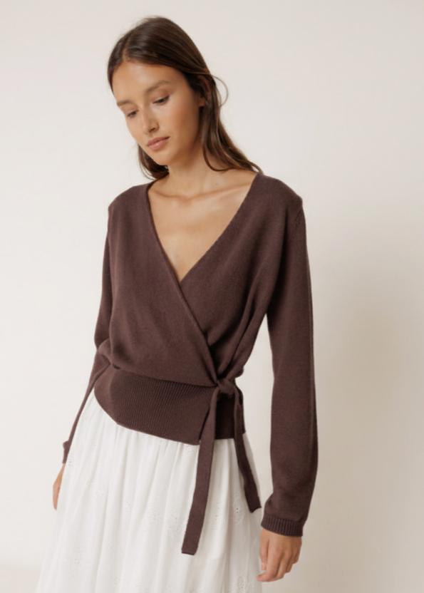 Woman wearing a brown wrap top with a white background