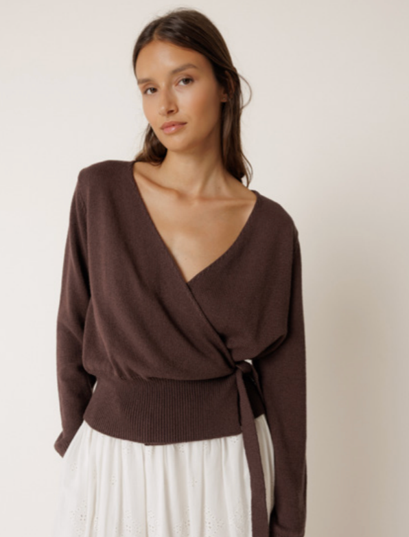 Woman wearing a brown knitted top with a plain background