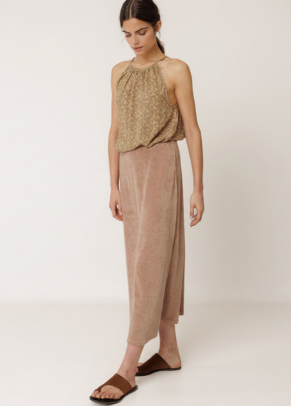 Woman wearing a patterned top and beige pants on a white background