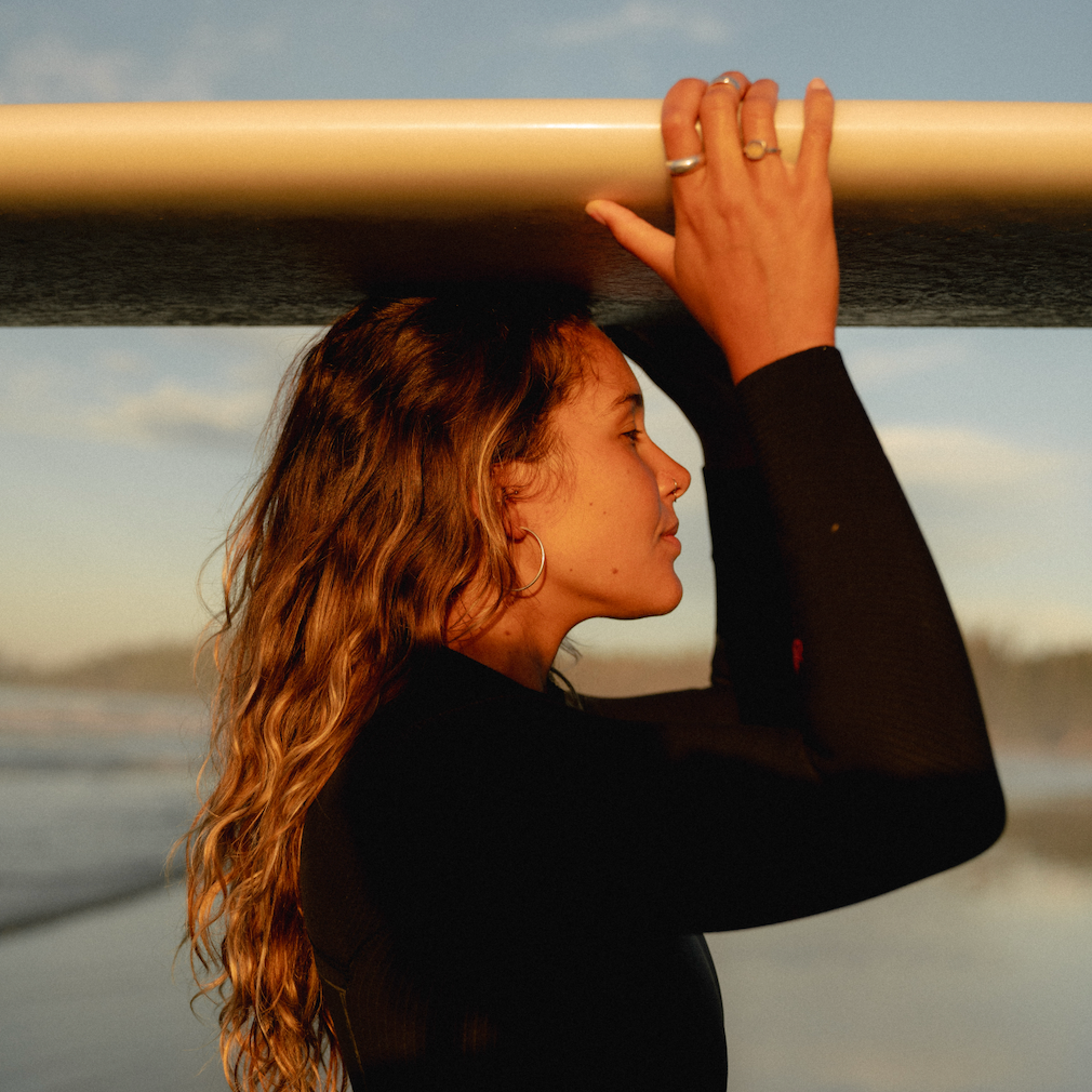 Person holding a surfboard with a scenic background
