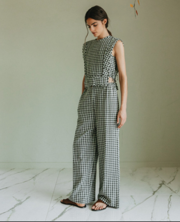 Woman wearing a black and white checkered outfit standing on a marble floor.