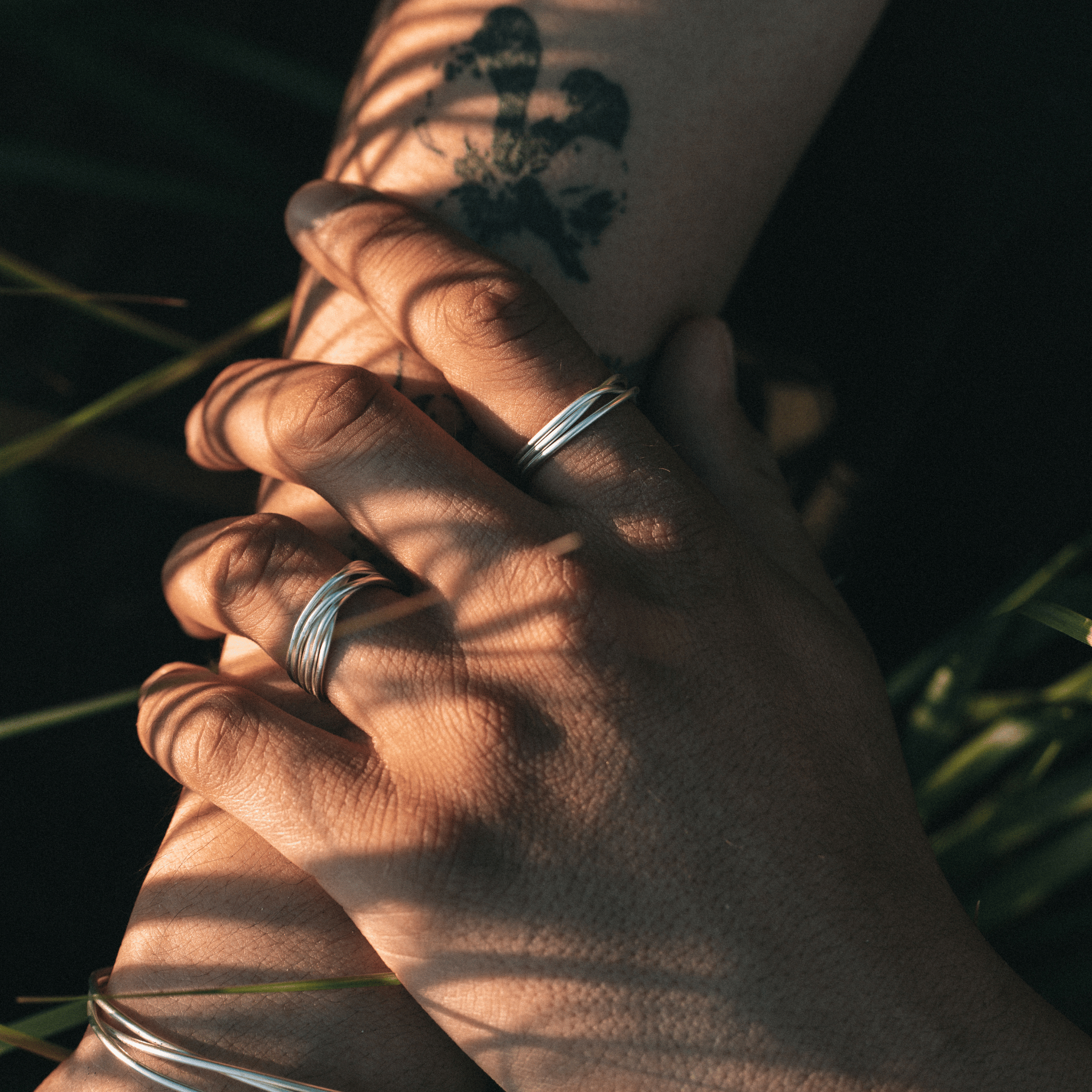 Two hands holding each other with a leafy background