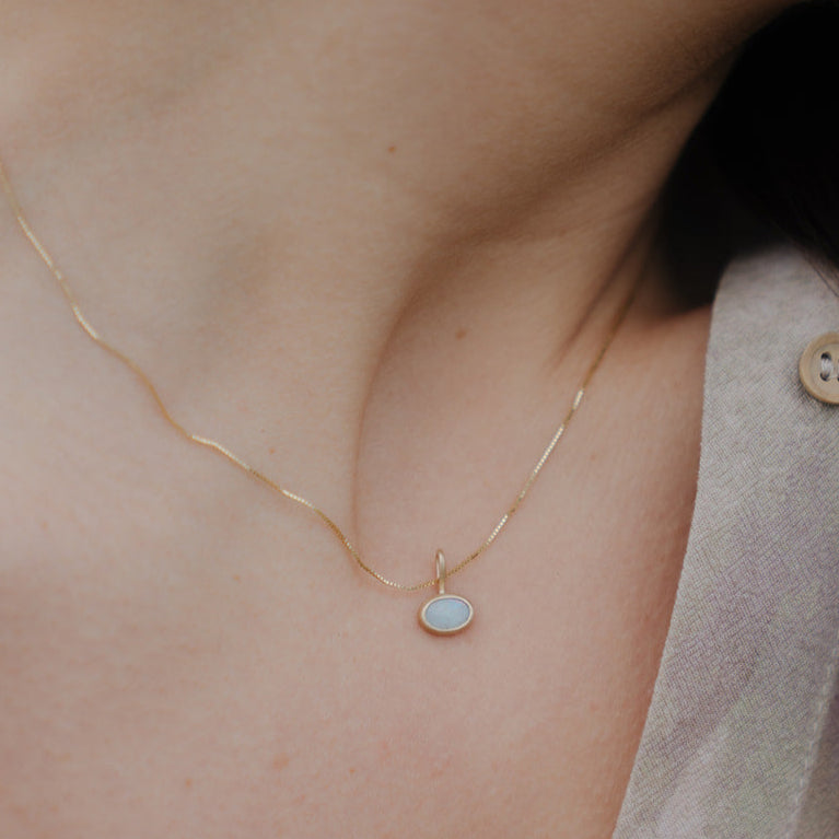 Necklace with a pendant worn by a person, close-up of the necklace on skin.